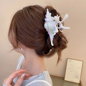 Detail of a large pearlescent conch shell hair claw clip holding hair in a chic bun