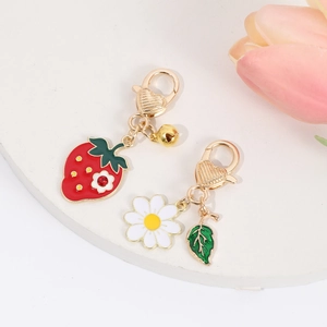 Detail of red strawberry and white daisy enamel charms with golden heart clasps