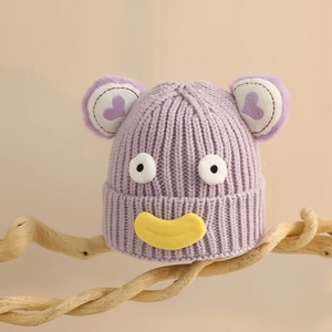 Détail d'un bonnet tricoté violet pour enfants avec de grands yeux et une bouche jaune