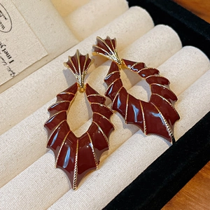 Gros plan détaillé de boucles d'oreilles papillon géométriques en émail bordeaux et or