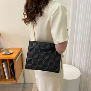 Detail of black geometric crossbody bag with 3D quilted texture and gold chain strap