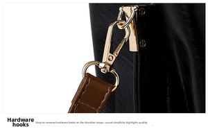 Macro shot of gold-tone metal hook and textured black leather shoulder bag strap