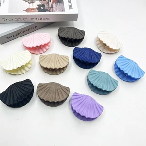 Flat lay of multiple shell-shaped matte hair claws in various colors on a white background