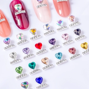Sparkling silver heart nail gems in various colors on display with manicure tips