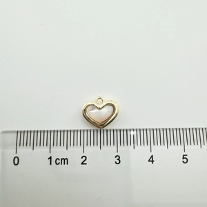 18K gold-plated heart pendant with white shell inlay shown on a ruler for scale