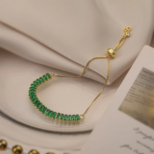 Elegant gold-plated bracelet with green zircon stones on silk fabric background