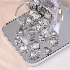 Gros plan de pendentifs cœur argentés avec perles sur plateau miroir pour bijoux DIY