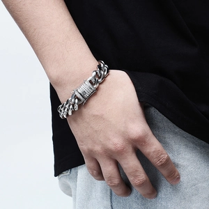 Macro shot of men's silver Cuban link bracelet with iced-out rhinestone buckle on wrist