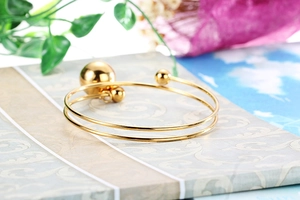 Macro detail of gold plated double layer open bangle with metallic ball accents