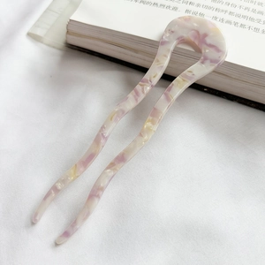 Detail showing wavy acetate U-shaped hair pin with marble texture on white fabric