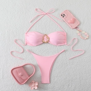 Detailed view of pink halter bikini set with gold ring ornament on soft plush background