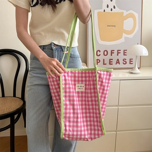 Detail of pink checkered canvas tote bag with green contrast trim in a lifestyle setting