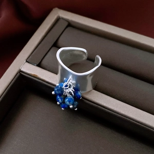 Detailed close-up of a wide irregular silver ring featuring blue beaded natural stones