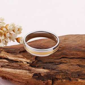 Bague en acier inoxydable bicolore argent et or poli sur fond de bois sombre texturé