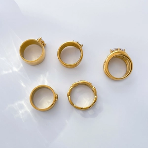 Detailed view of five 18K gold plated titanium rings with zircon stones and wavy textures