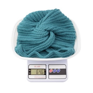 Close-up of a blue knitted headband with a cross knot showing weight of 64.6g on a scale