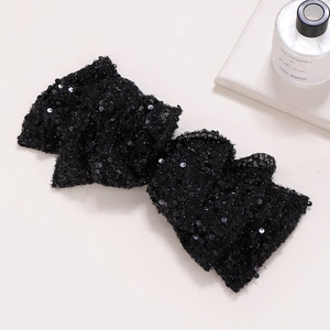 Elegant large black sequin bow hair clip for women on a minimalist beige background