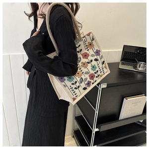 Linen tote bag with floral print and thick rope handles shown on a shoulder