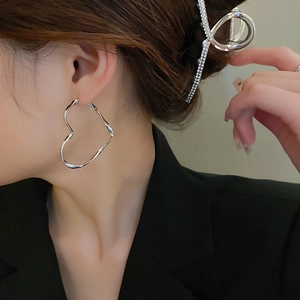 Model wearing silver heart-shaped hoop earrings and sparkling rhinestone hair clip