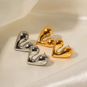 Polished 18K gold and silver plated heart stud earrings on elegant silk fabric