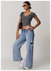 Detailed view of dark grey V-neck knitted T-shirt paired with light blue distressed jeans