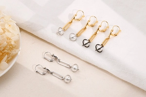 Detail of elegant pearl drop earrings in gold and silver finish on textured fabric