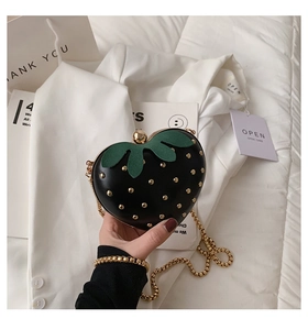Detail of strawberry heart bag in black PU leather with gold studs and chain strap