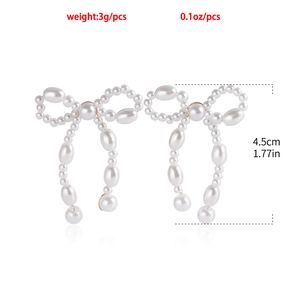 Detail view of handmade pearl bow earrings showing 4.5cm height and 3g weight specifications