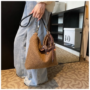 Brown wool-like crossbody bag with a leather dog charm and sleek black shoulder strap
