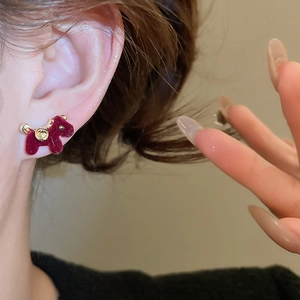 Detailed close-up of a burgundy flocked dog earring with golden collar on ear