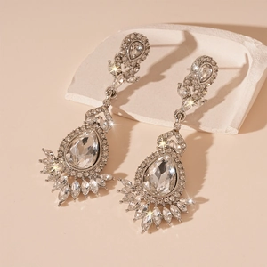 Macro shot of sparkling silver drop earrings with marquise crystals on a stone display