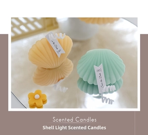Close-up of shell-shaped scented candles in mint and orange with Save the Date labels