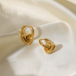Boucles d'oreilles créoles coeur en acier doré 14K sur un fond de tissu en soie