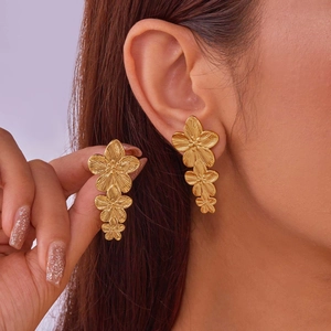 Close-up of triple layered golden flower dangle earrings with brushed metal texture