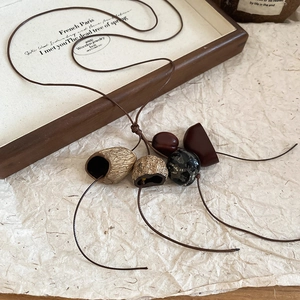 Detail of vintage necklace featuring natural nut shell and stone pendants on brown cord