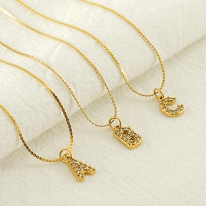 Close-up of gold stainless steel necklaces featuring A, B, and C initial pendants with crystals