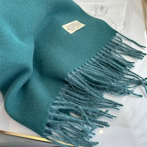 Detail of dark teal cashmere-style scarf showing soft twill weave and long fringe edges