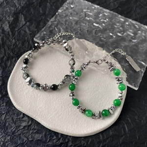 Detailed close-up of cat eye stone and obsidian bead bracelets with steel pendants