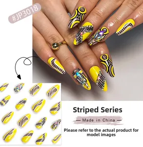 Macro detail of striped press-on nails with sparkling yellow patterns and colorful rhinestones