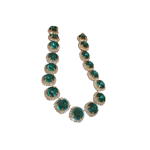 Luxurious gold necklace featuring green gemstones surrounded by clear crystals