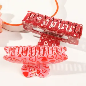 Close-up of pink and red acrylic claw clips with heart patterns in a two-piece set
