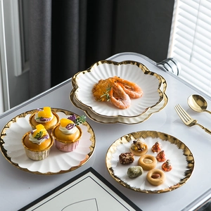 Three-piece set of white ceramic plates with gold rims and elegant petal-shaped edges