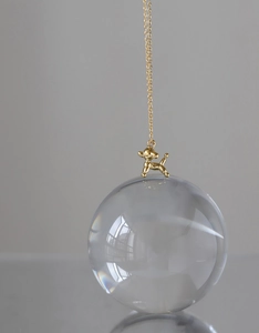 Detail of 18K gold-plated balloon dog pendant necklace on O-chain over crystal ball