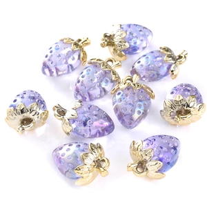 Macro shot of purple translucent strawberry charms with gold leaf accents for DIY crafts