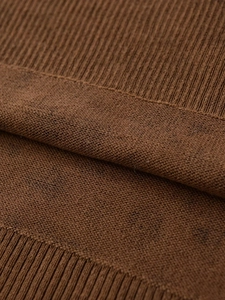 Close-up of brown knit sweater texture showing detailed ribbed cuffs and soft stitch patterns
