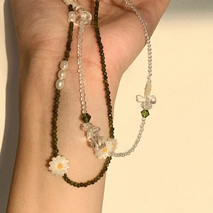 Detail of layered S925 beaded necklace with green zircon daisies and freshwater pearls