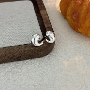 Detail of teardrop silver earrings on a wooden tray with a minimalist aesthetic style