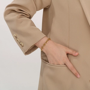 Close-up of golden stainless steel pig nose anchor link bracelet on a fashion model