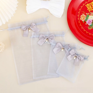 Detail view of four grey organza gift bags with satin bows and pearl charms in various sizes