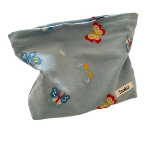 Light blue cosmetic bag featuring colorful butterfly embroidery and a secure zip closure